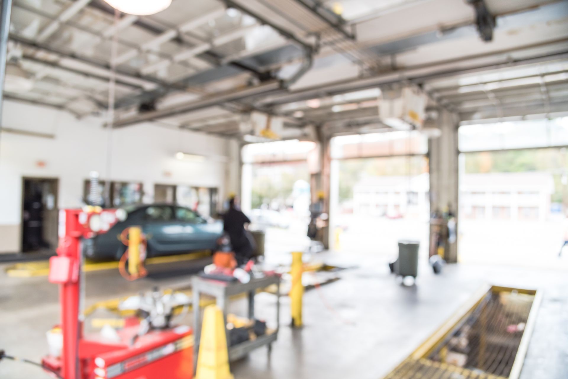 Blurred image of car in auto shop. Defocused background of modern repair shop. Small car oil change service station at Little Rock, Arkansas, US. Interior of car repair shop with working auto mechanic