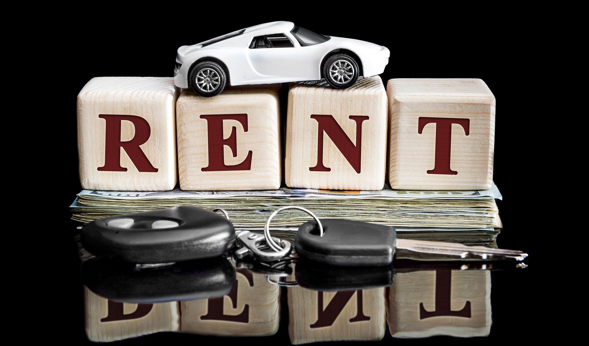 Wooden cubes with word RENT, car model, money and car keys on black reflective background.