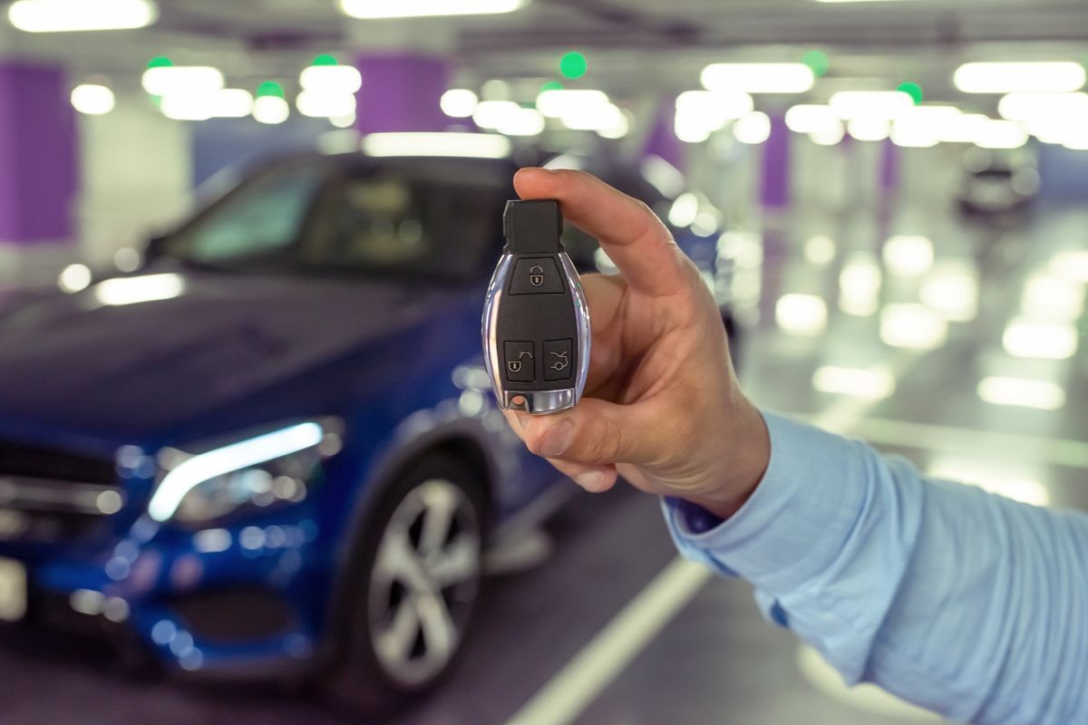 Car keys in a hand of the person against the background of the car. underground parking.